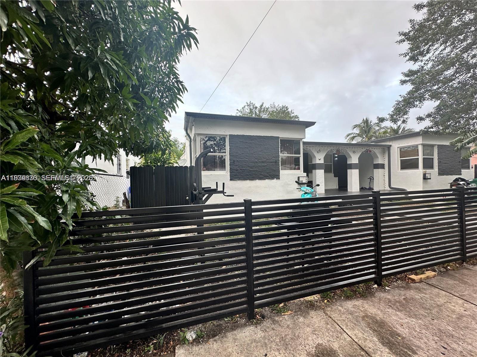 A single-story house with a black horizontal slat fence and a dark-painted brick facade — 101 NW 68th Ter, Miami FL 33150, MIAMI, FL
