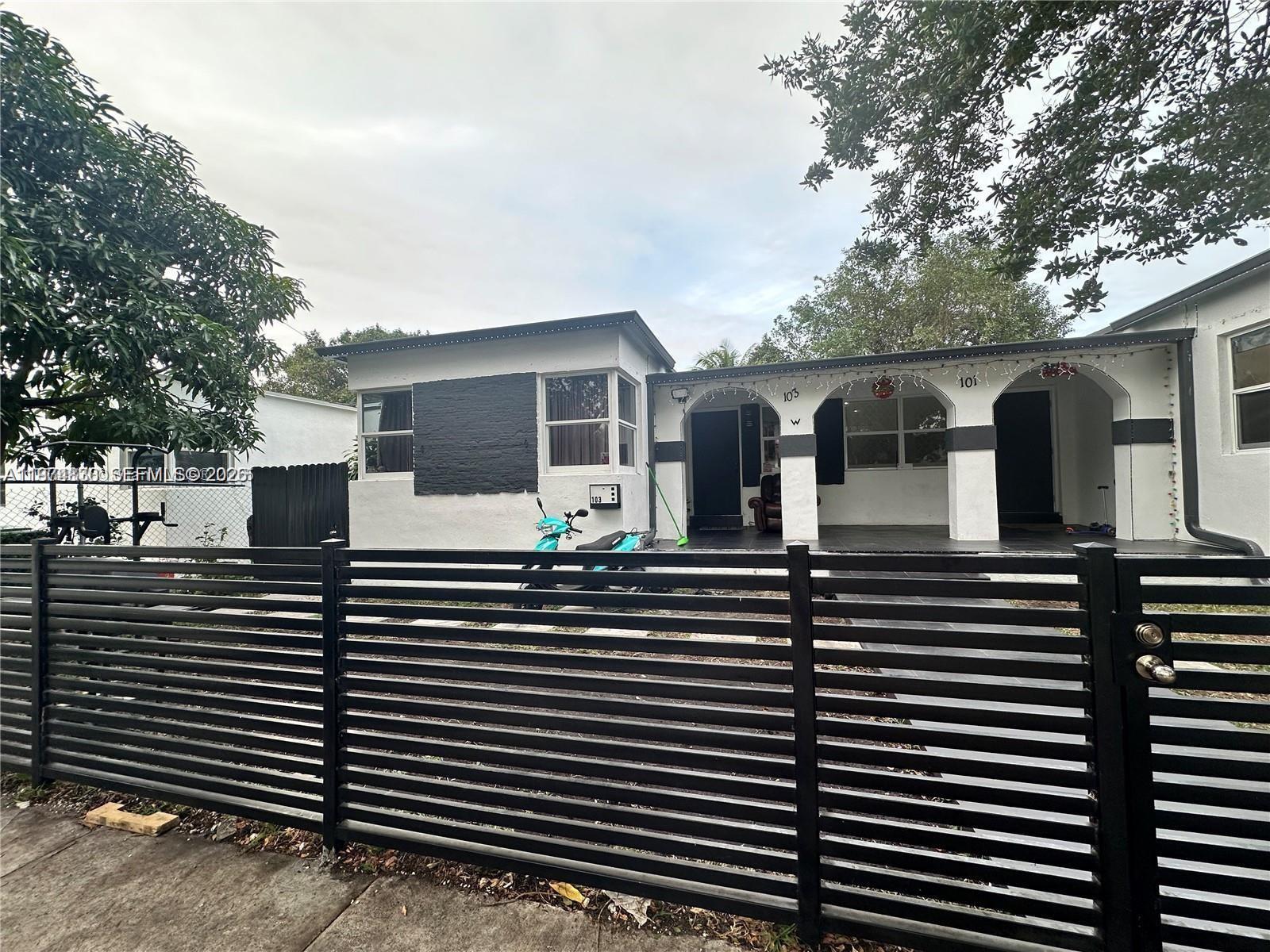 A single-story house with a black horizontal fence and a covered front porch with arches — 101 NW 68th Ter, Miami FL 33150, MIAMI, FL