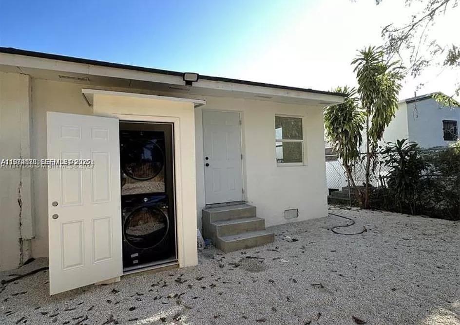 An exterior view shows a white building with a stacked washer and dryer unit outside — 101 NW 68th Ter, Miami FL 33150, MIAMI, FL