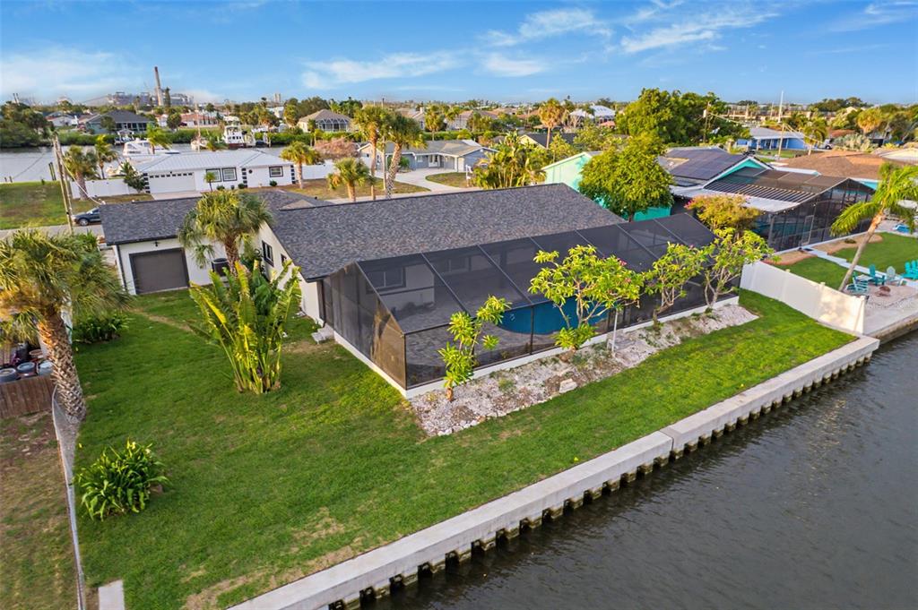 An aerial view of a waterfront house with a screened-in pool and a concrete seawall — 728 SPANISH MAIN DRIVE, APOLLO BEACH, FL
