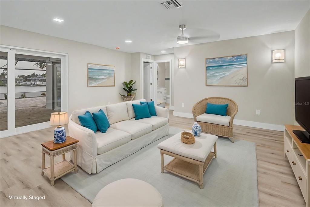 A modern kitchen features white cabinetry, a stone-topped island with wicker stools, and stainless appliances — 728 SPANISH MAIN DRIVE, APOLLO BEACH, FL