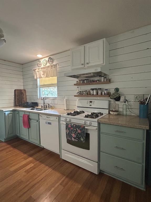 A kitchen features light green cabinets, white shiplap walls, a white stove, and wood flooring — 14635 DUPREE ROAD, WIMAUMA, FL