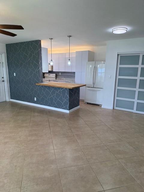 A kitchen with a wood-topped island and a geometric-patterned accent wall sits off a tiled room — 115 Lakes End Drive Apt D, Fort Pierce FL 34982, FORT PIERCE, FL