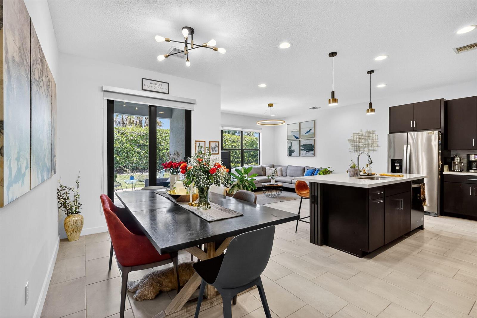 An open-concept dining area and kitchen with dark cabinetry, a central island, and tile flooring — 4388 Serpens Lane, Lake Worth FL 33467, LAKE WORTH, FL