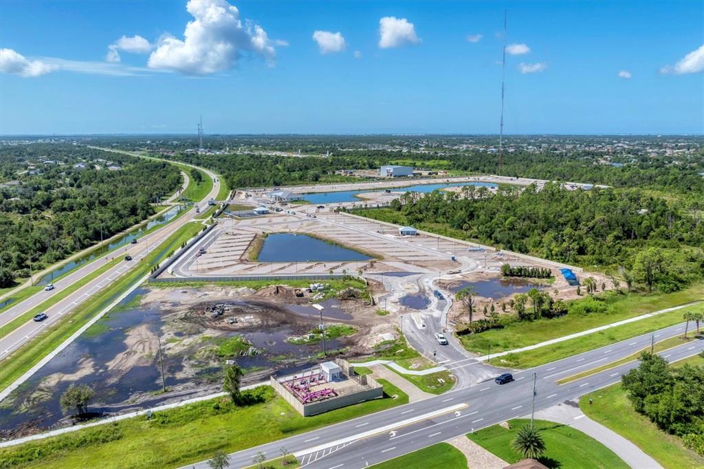 An aerial view shows a construction site with a parking lot, retention ponds, and roads — 9001 GASPARILLA ROAD UNIT 6, ROTONDA WEST, FL
