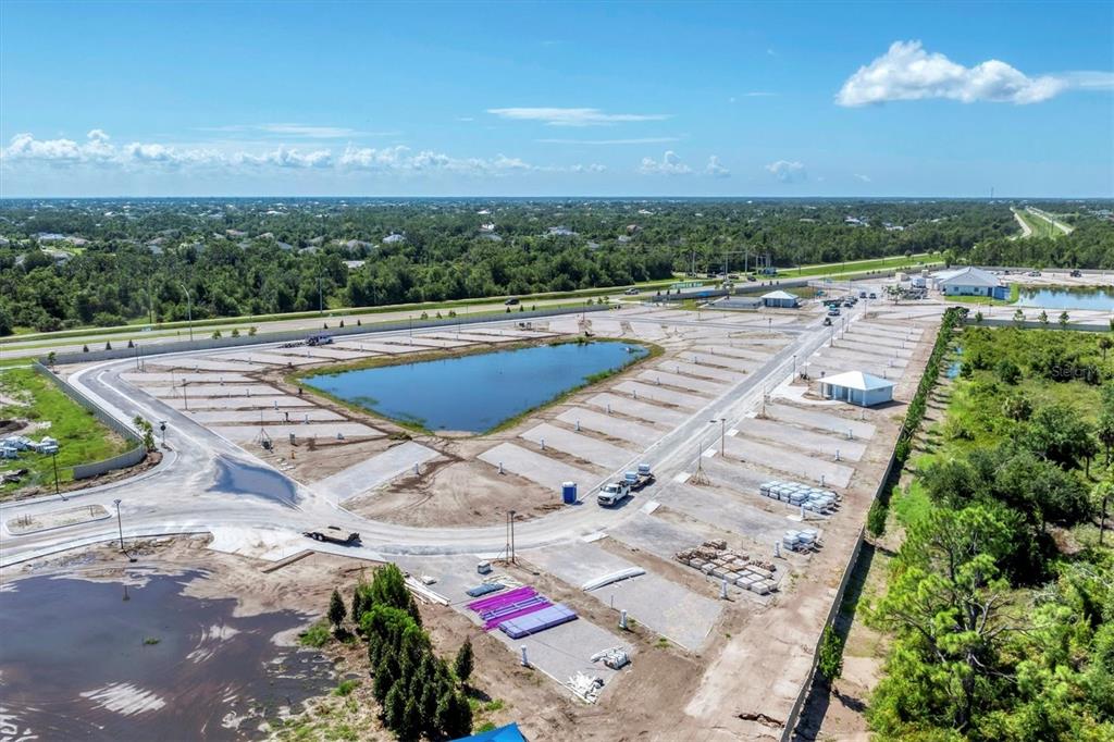 An aerial view shows a residential development site with a central pond and paved lots — 9001 GASPARILLA ROAD UNIT 6, ROTONDA WEST, FL