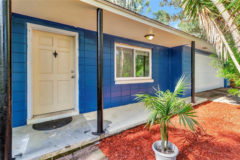 A blue concrete block house exterior features a beige front door and a covered porch — 13420 SE 122ND PLACE, OCKLAWAHA, FL