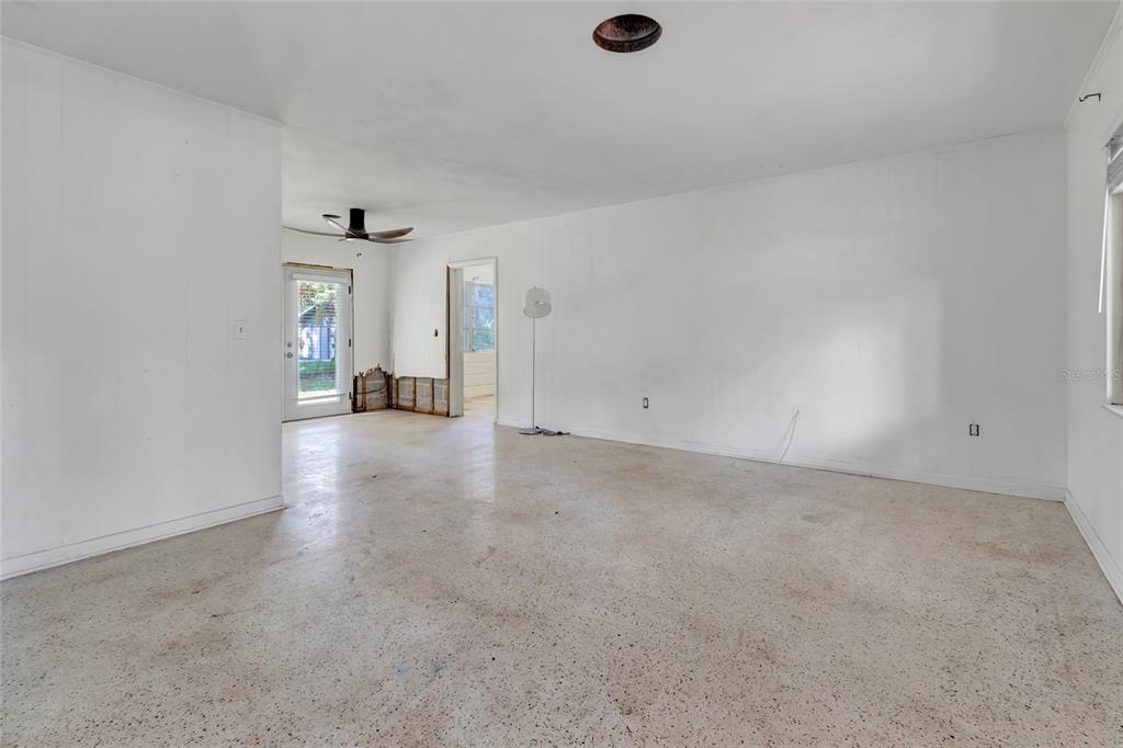 An empty living room features white walls, a speckled concrete floor, and a ceiling fan — 13420 SE 122ND PLACE, OCKLAWAHA, FL