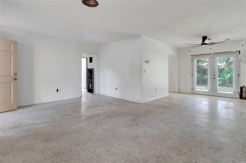 An empty room with white walls, a speckled concrete floor, and glass patio doors — 13420 SE 122ND PLACE, OCKLAWAHA, FL
