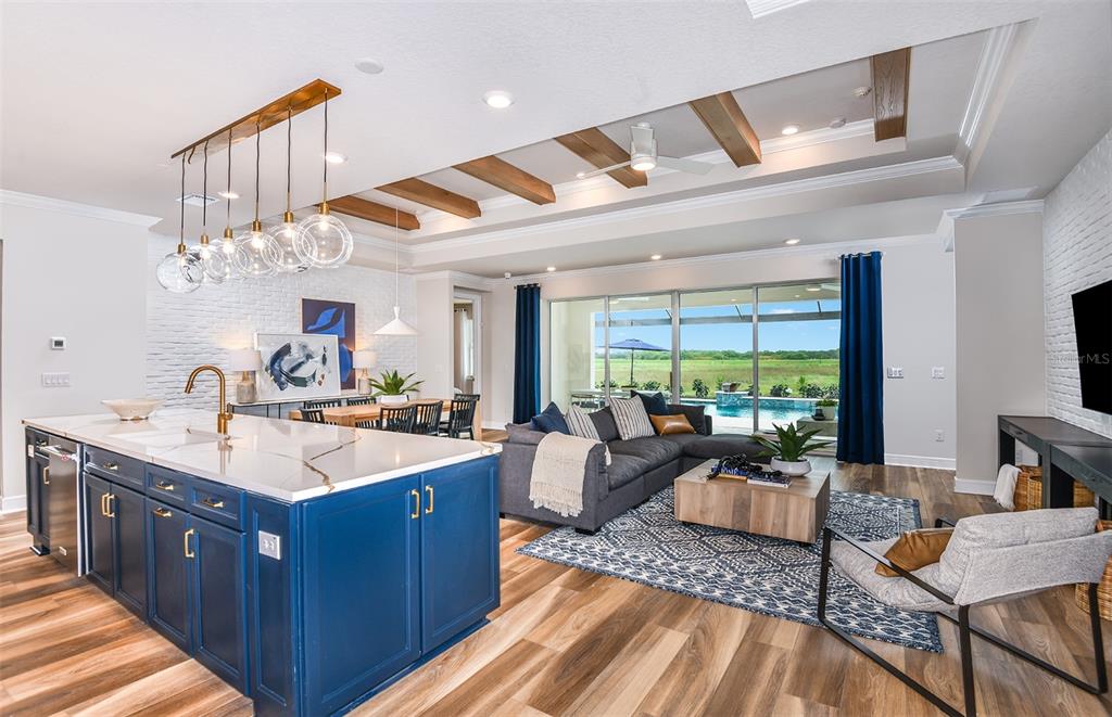 A modern open-concept kitchen and living area featuring a blue island and wood ceiling beams — 14421 DAYSTAR COURT, PARRISH, FL