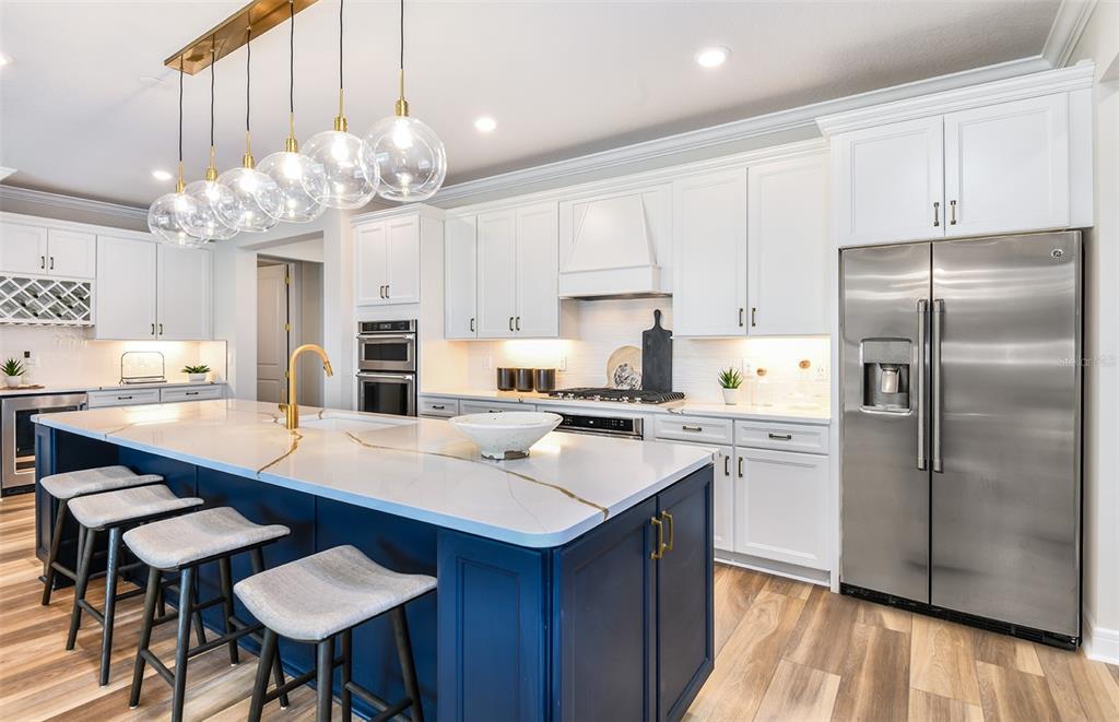 A modern kitchen features a blue island with white countertops, white cabinetry, and stainless appliances — 14421 DAYSTAR COURT, PARRISH, FL