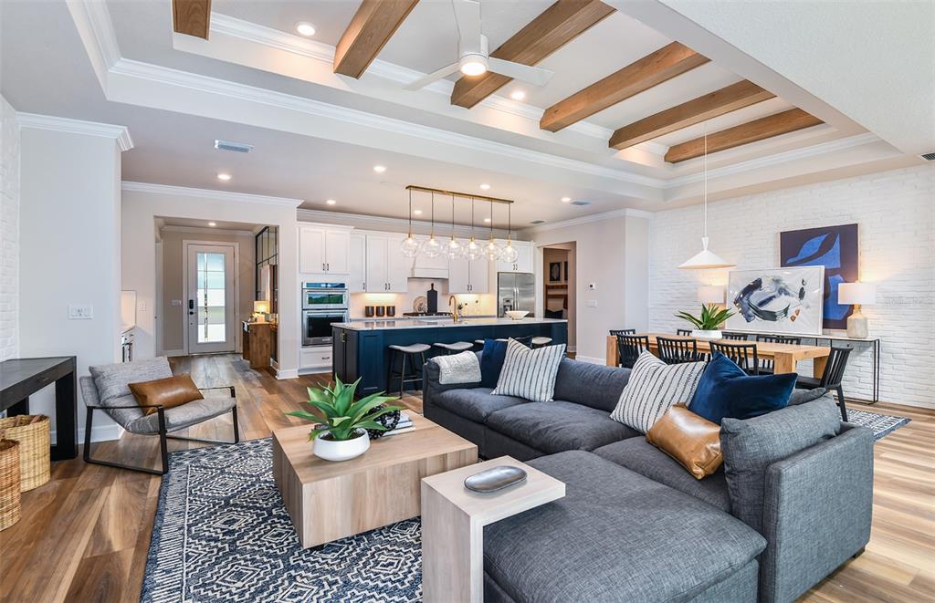 An open-concept living room and kitchen feature wood ceiling beams and a large sectional sofa — 14421 DAYSTAR COURT, PARRISH, FL