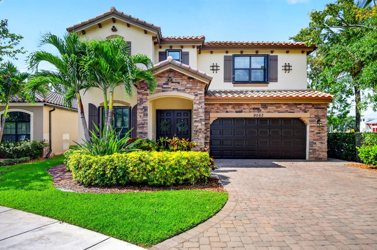 A two-story house with a stone facade, a two-car garage, and a landscaped front yard — 9062 Gulf Cove Drive, Wellington FL 33467, WELLINGTON, FL