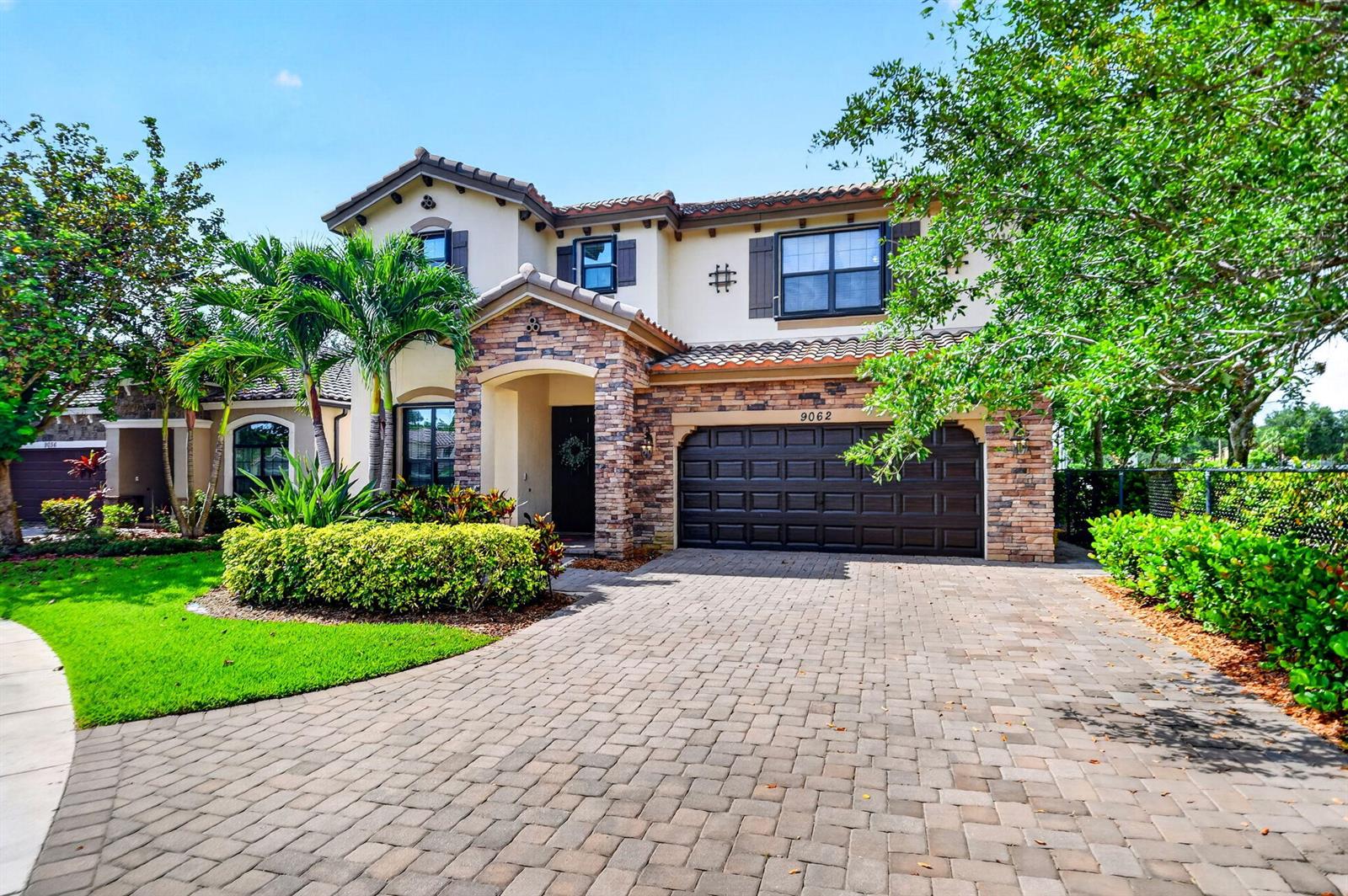 A two-story suburban house with a stone facade, tile roof, and a paved driveway — 9062 Gulf Cove Drive, Wellington FL 33467, WELLINGTON, FL