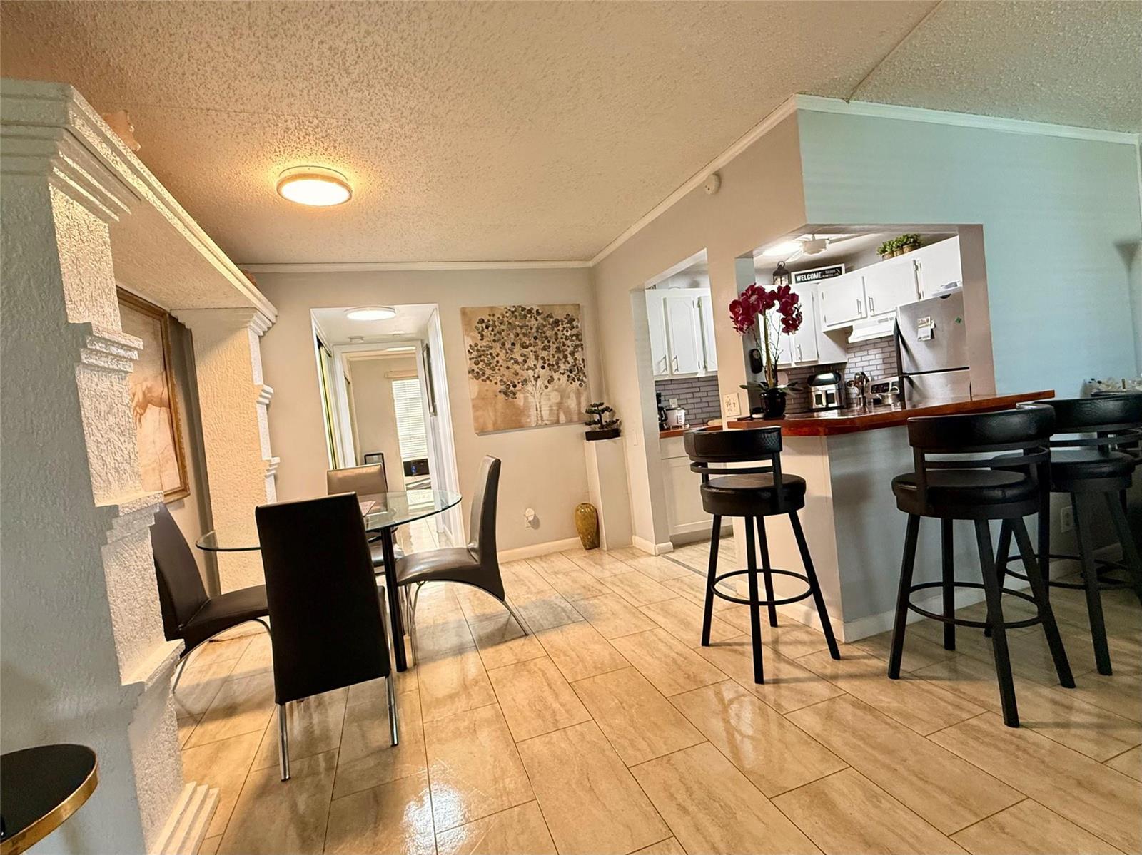 A dining area with a glass table and a kitchen with a breakfast bar — 355 Oakridge T # 355, Deerfield Beach FL 33442, DEERFIELD BEACH, FL