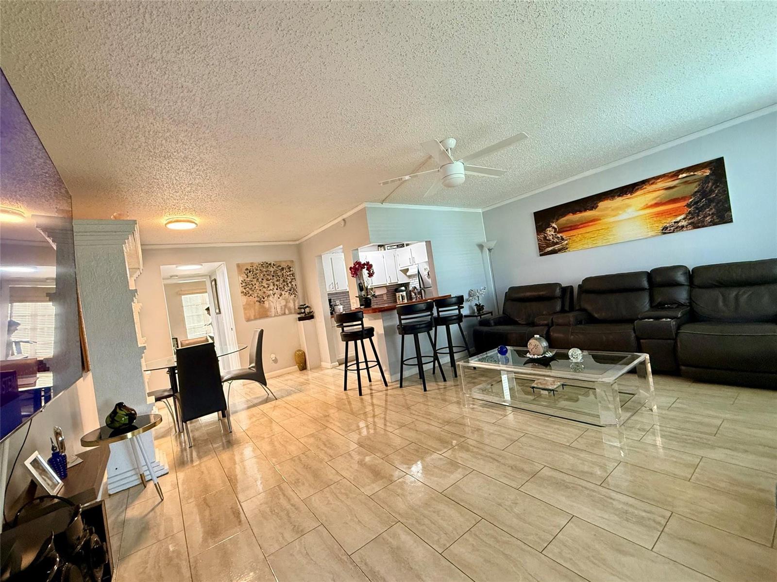 An open-concept living and dining area features tile flooring, a breakfast bar, and leather seating — 355 Oakridge T # 355, Deerfield Beach FL 33442, DEERFIELD BEACH, FL