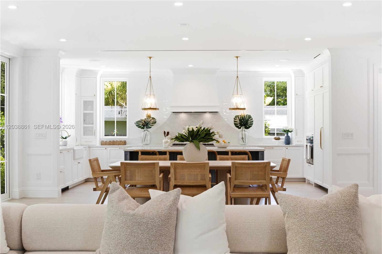 A bright kitchen features white cabinetry, a central island, and a wooden dining table — 6751 SW 76th Ter, South Miami FL 33143, SOUTH MIAMI, FL