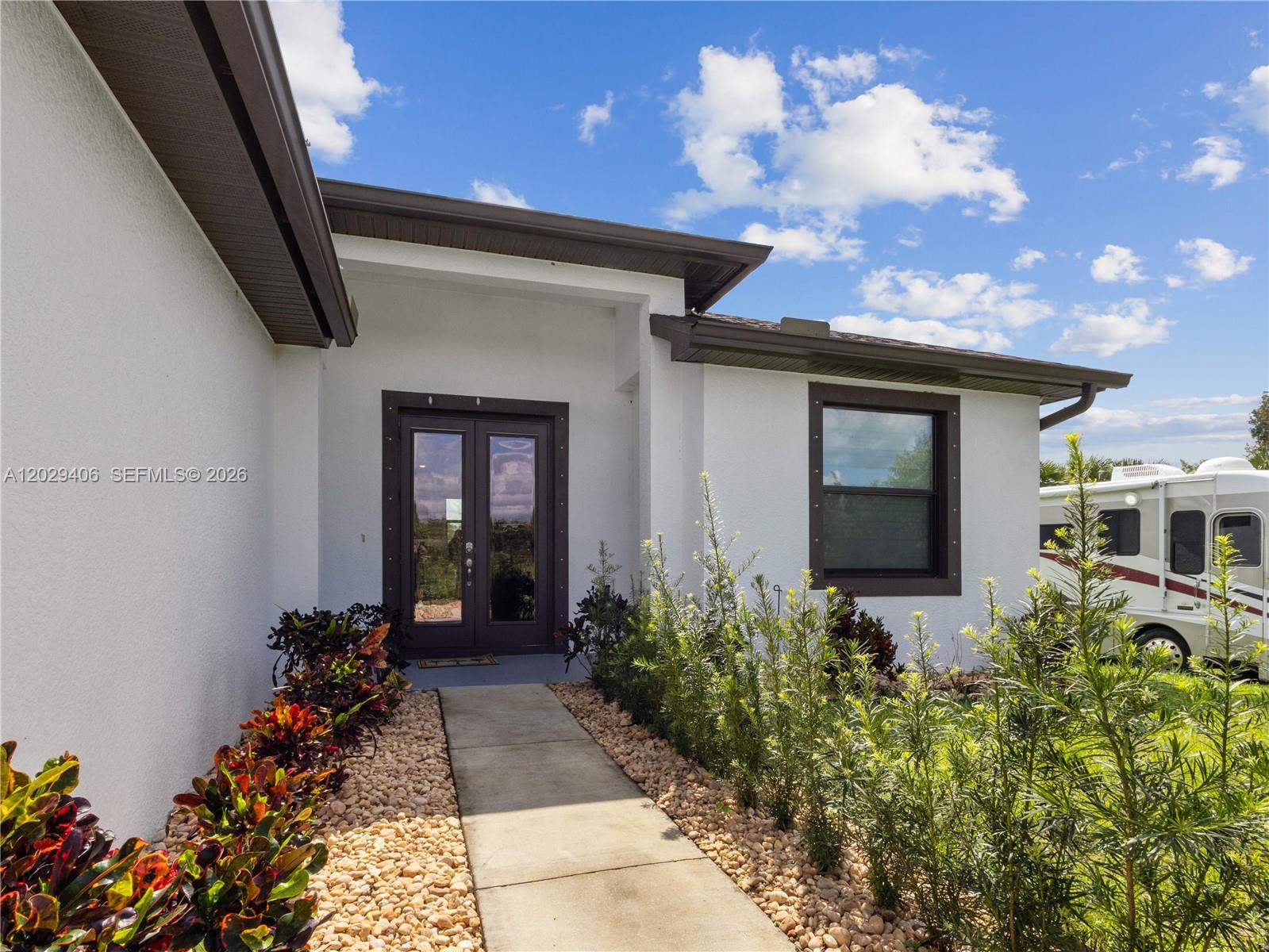 A white house exterior features a double front door, a walkway, and landscaping — 490 NW 37 AV., Naples FL 34120, NAPLES, FL
