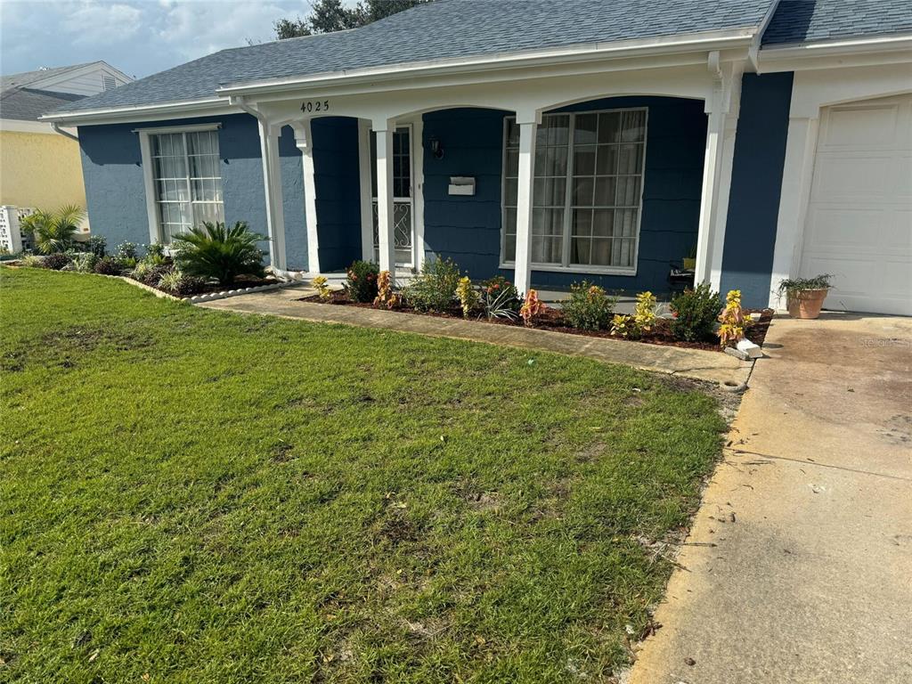 A blue house with a white-trimmed porch, a front lawn, and a concrete driveway — 4025 GRAYTON DRIVE, NEW PORT RICHEY, FL