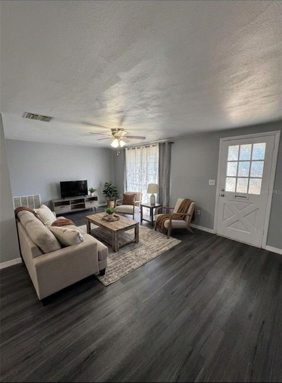 A living room features light gray walls, dark wood-look flooring, a sofa, and a front door — 4025 GRAYTON DRIVE, NEW PORT RICHEY, FL