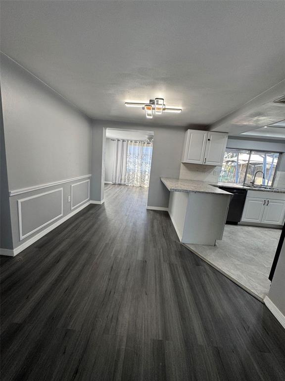 A kitchen with white cabinets and a peninsula opens into a dining area with wainscoting — 4025 GRAYTON DRIVE, NEW PORT RICHEY, FL