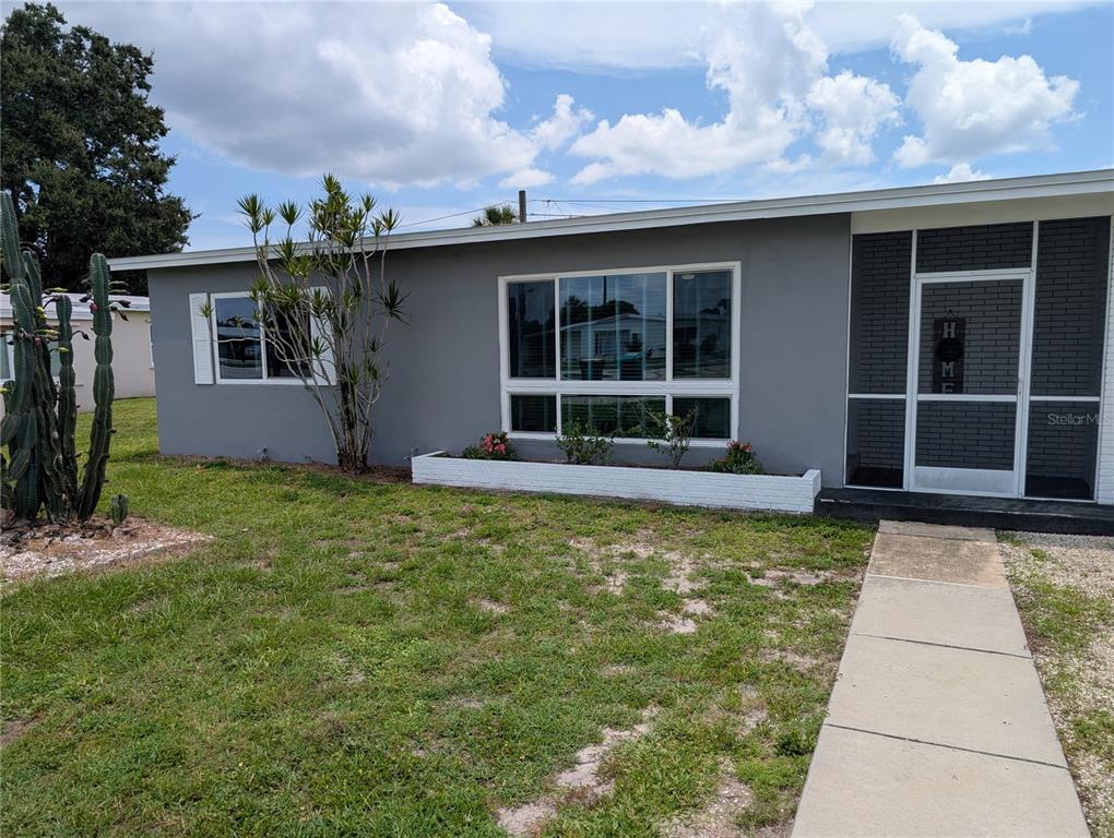 A gray single-story house features a white planter box, a large window, and a screened entrance — 22311 MIDWAY BOULEVARD, PORT CHARLOTTE, FL