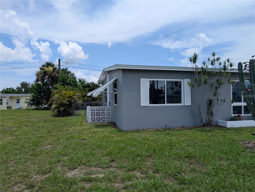 A gray exterior wall of a house features a window with white shutters and a breeze-block wall — 22311 MIDWAY BOULEVARD, PORT CHARLOTTE, FL