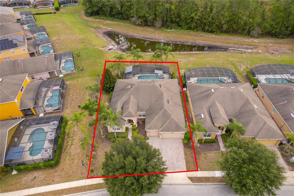 An aerial view shows a single-family home with a pool enclosure and a paved driveway — 124 YELLOW SNAPDRAGON DRIVE, DAVENPORT, FL
