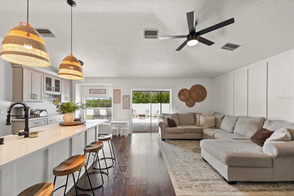 A modern open-concept kitchen and living area featuring a large island, sectional sofa, and patio — 4529 MARCHMONT BOULEVARD, LAND O LAKES, FL