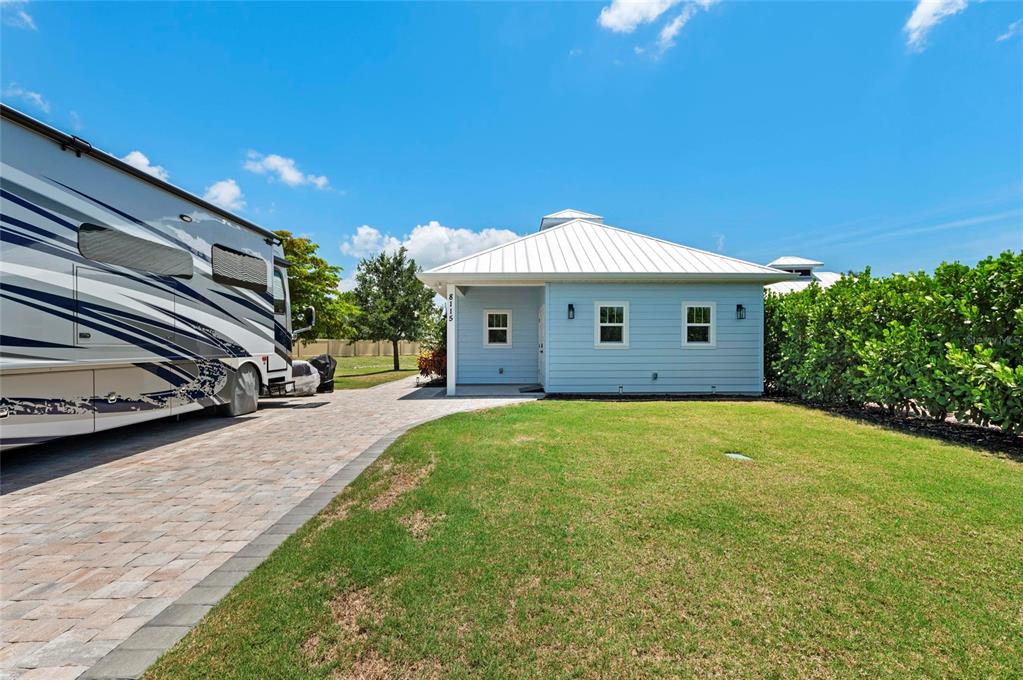 A light blue house with a white metal roof stands next to a paved driveway — 8115 SW SAND CRANE CIRCLE LOT 2, ARCADIA, FL