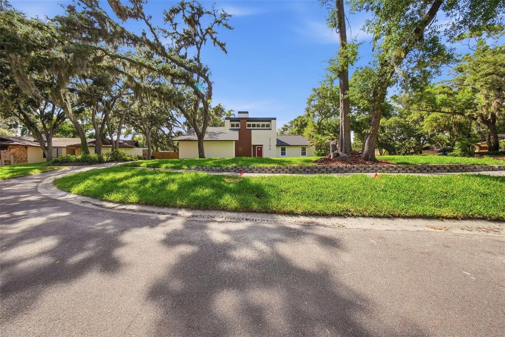 A modern house with a brown central accent wall sits behind a curved stone retaining wall — 2104 DOEFIELD COURT, VALRICO, FL