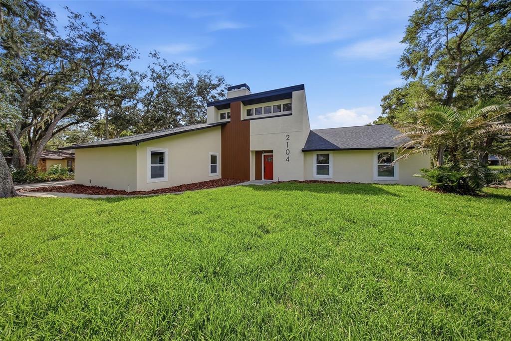 A single-story house with a modern facade, a red front door, and a prominent chimney — 2104 DOEFIELD COURT, VALRICO, FL
