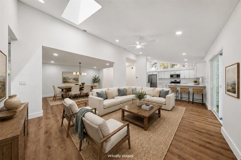 A virtually staged open-concept living and dining area with vaulted ceilings and wood-look flooring — 2104 DOEFIELD COURT, VALRICO, FL