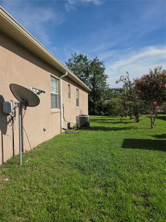 The side exterior of a tan house features a satellite dish and an air conditioning unit — 7957 SW 103RD LOOP, OCALA, FL