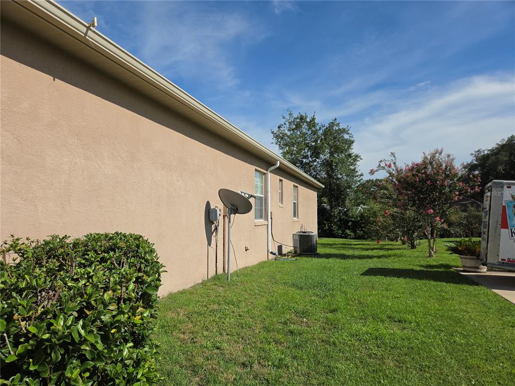 A side view of a beige stucco house with a satellite dish and air conditioner — 7957 SW 103RD LOOP, OCALA, FL