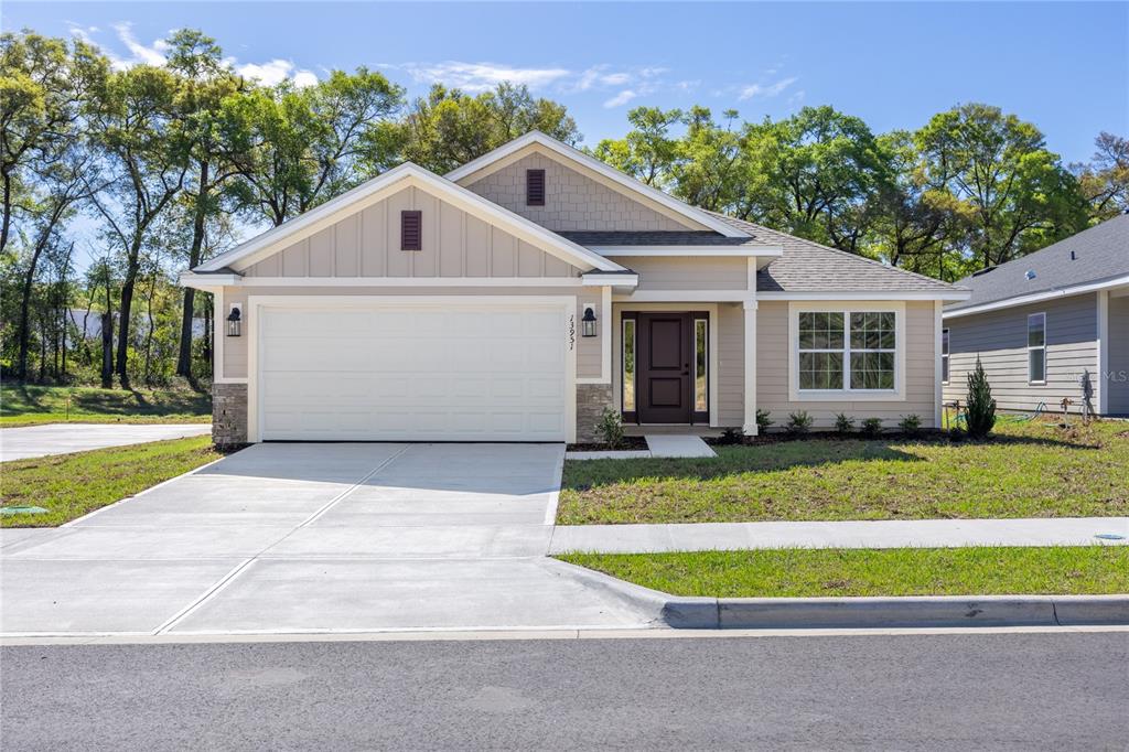 A single-story house with beige siding, a two-car garage, and a dark front door — 17788 NW 168TH ROAD, ALACHUA, FL