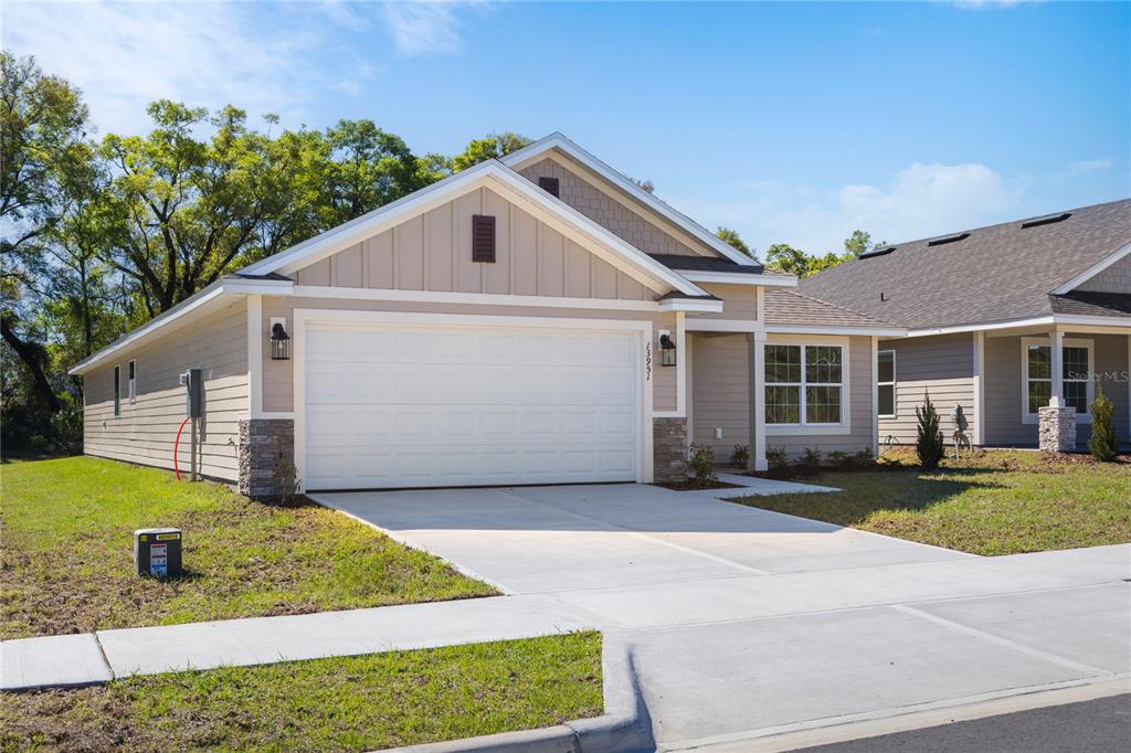 A single-story house with a two-car garage, light siding, and a concrete driveway — 17788 NW 168TH ROAD, ALACHUA, FL