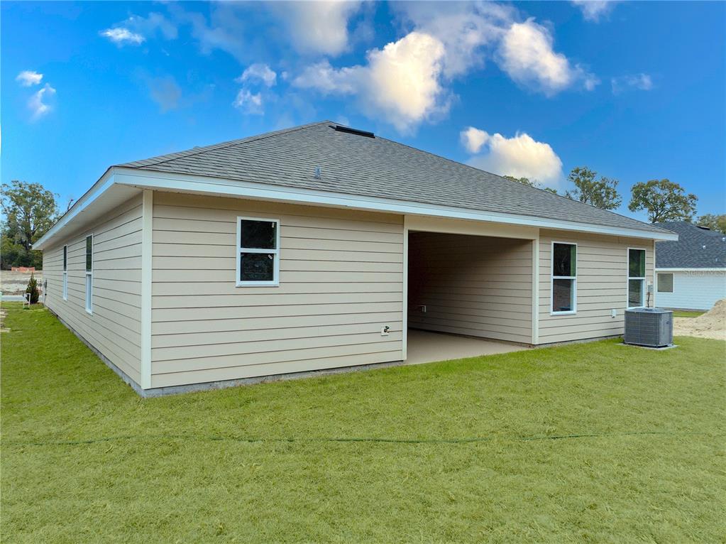 The exterior of a tan, single-story house features a covered patio and a grassy yard — 17788 NW 168TH ROAD, ALACHUA, FL