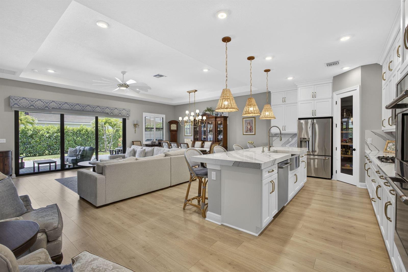 An open-concept kitchen and living area with a large island, white cabinetry, and sliding doors — 15830 Key Biscayne Lane, Westlake FL 33470, WESTLAKE, FL