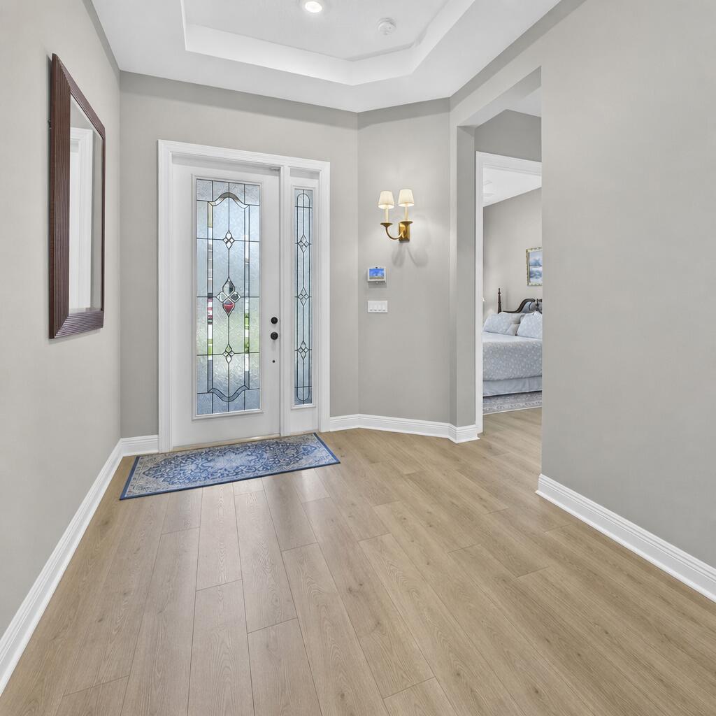 A bright entryway features light wood flooring, a decorative glass front door, and gray walls — 15830 Key Biscayne Lane, Westlake FL 33470, WESTLAKE, FL