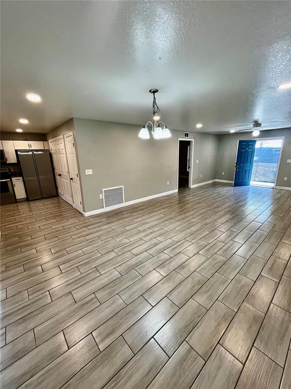 An open-concept living and dining area features light wood-look tile flooring and a blue door — 1705 3RD STREET NW UNIT A, WINTER HAVEN, FL