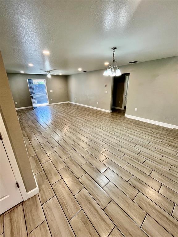 An open-concept room features light wood-look tile flooring, recessed lighting, and a chandelier — 1705 3RD STREET NW UNIT A, WINTER HAVEN, FL