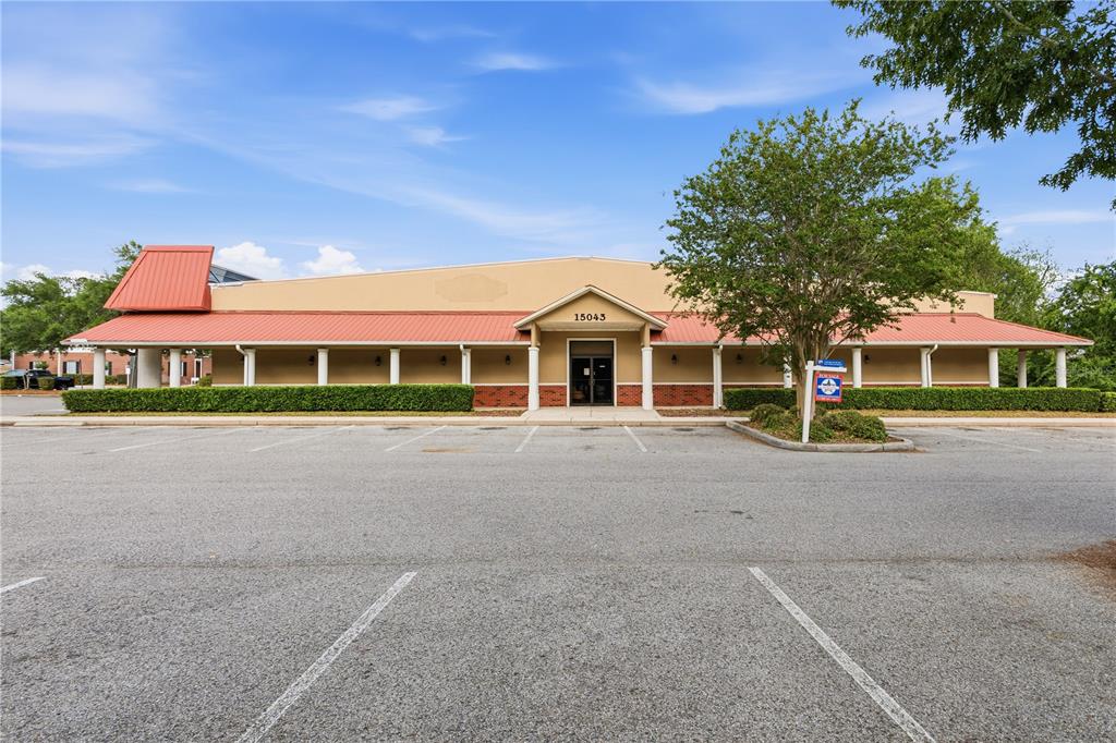 A single-story commercial building with a red metal roof and a large parking lot — 15043 MAIN STREET, ALACHUA, FL