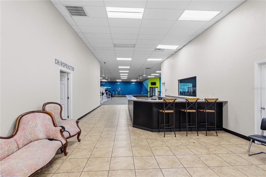A commercial interior features a reception desk, waiting area with vintage sofas, and gym equipment — 15043 MAIN STREET, ALACHUA, FL
