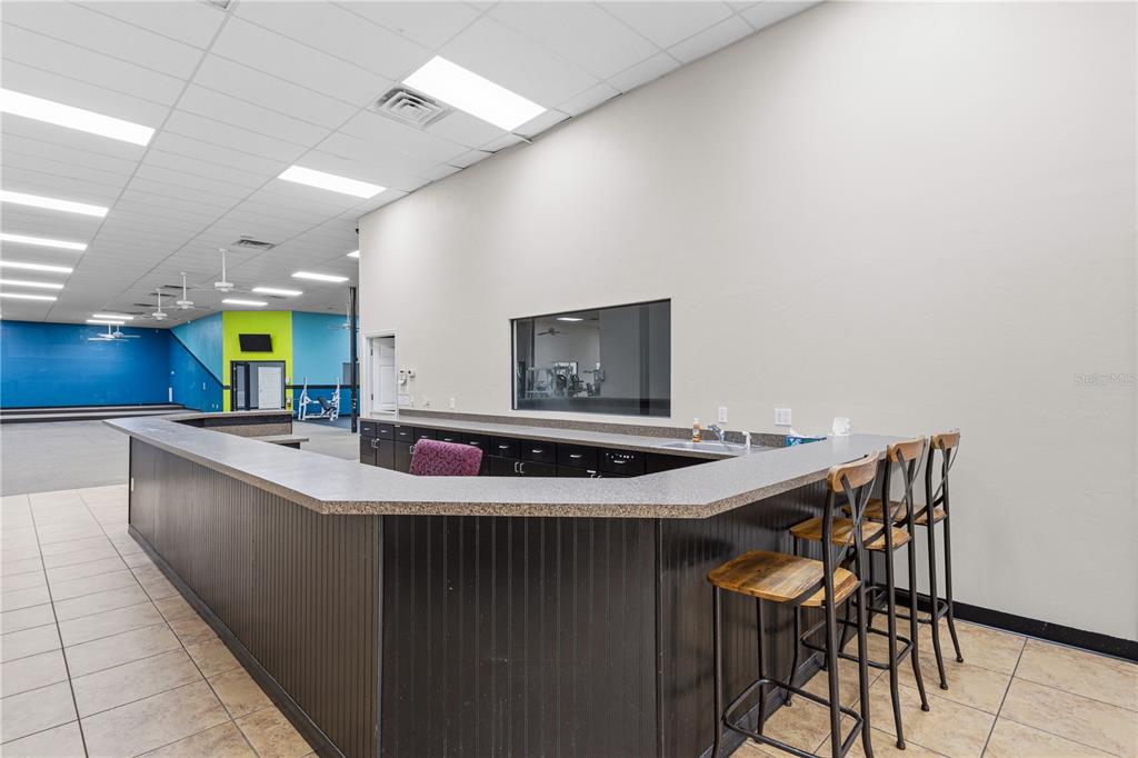 A reception desk with a dark counter and bar stools sits in a large room — 15043 MAIN STREET, ALACHUA, FL