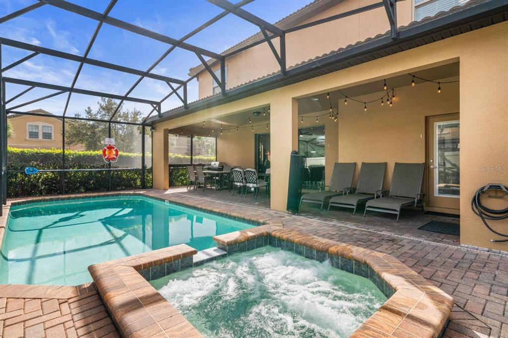 A screened-in patio features a swimming pool, a hot tub, and outdoor lounge furniture — 8879 MENTON LOOP, KISSIMMEE, FL