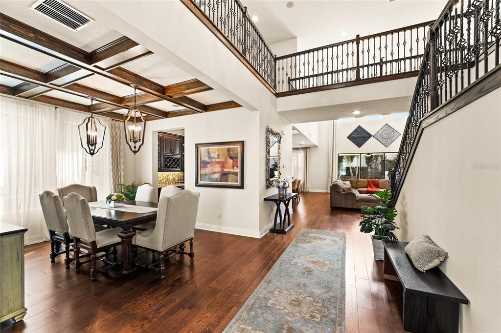 A dining area with coffered ceilings and a staircase overlooks a living room — 13596 GORGONA ISLE DRIVE, WINDERMERE, FL