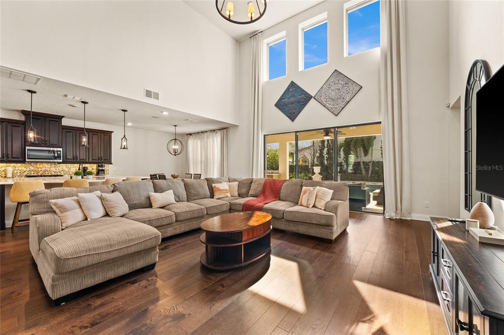 A spacious living room with high ceilings, a large sectional sofa, and hardwood floors — 13596 GORGONA ISLE DRIVE, WINDERMERE, FL