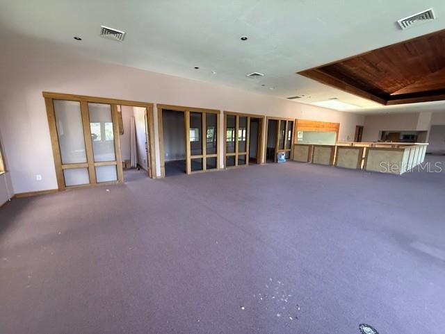 A large, open-concept room features purple carpeting, wood-trimmed glass partitions, and a recessed wooden ceiling — 5736 S TEXAS AVENUE, ORLANDO, FL