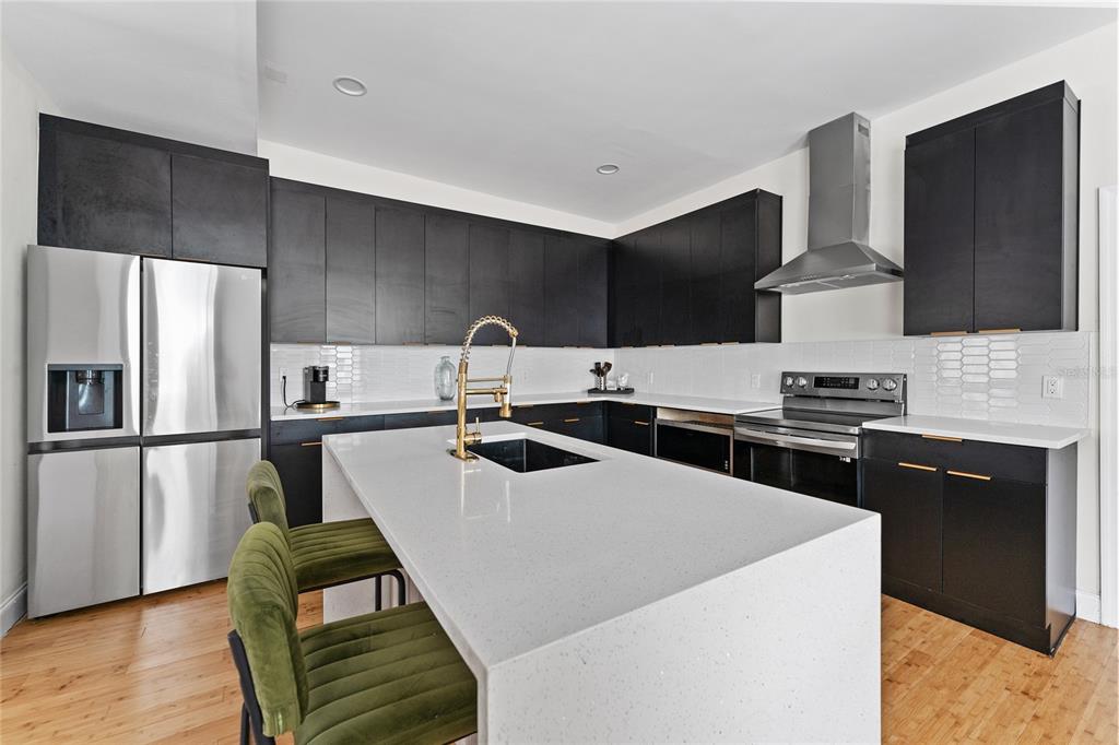 A modern kitchen features black cabinetry, a white quartz island, and stainless steel appliances — 680 25TH AVENUE S, ST PETERSBURG, FL